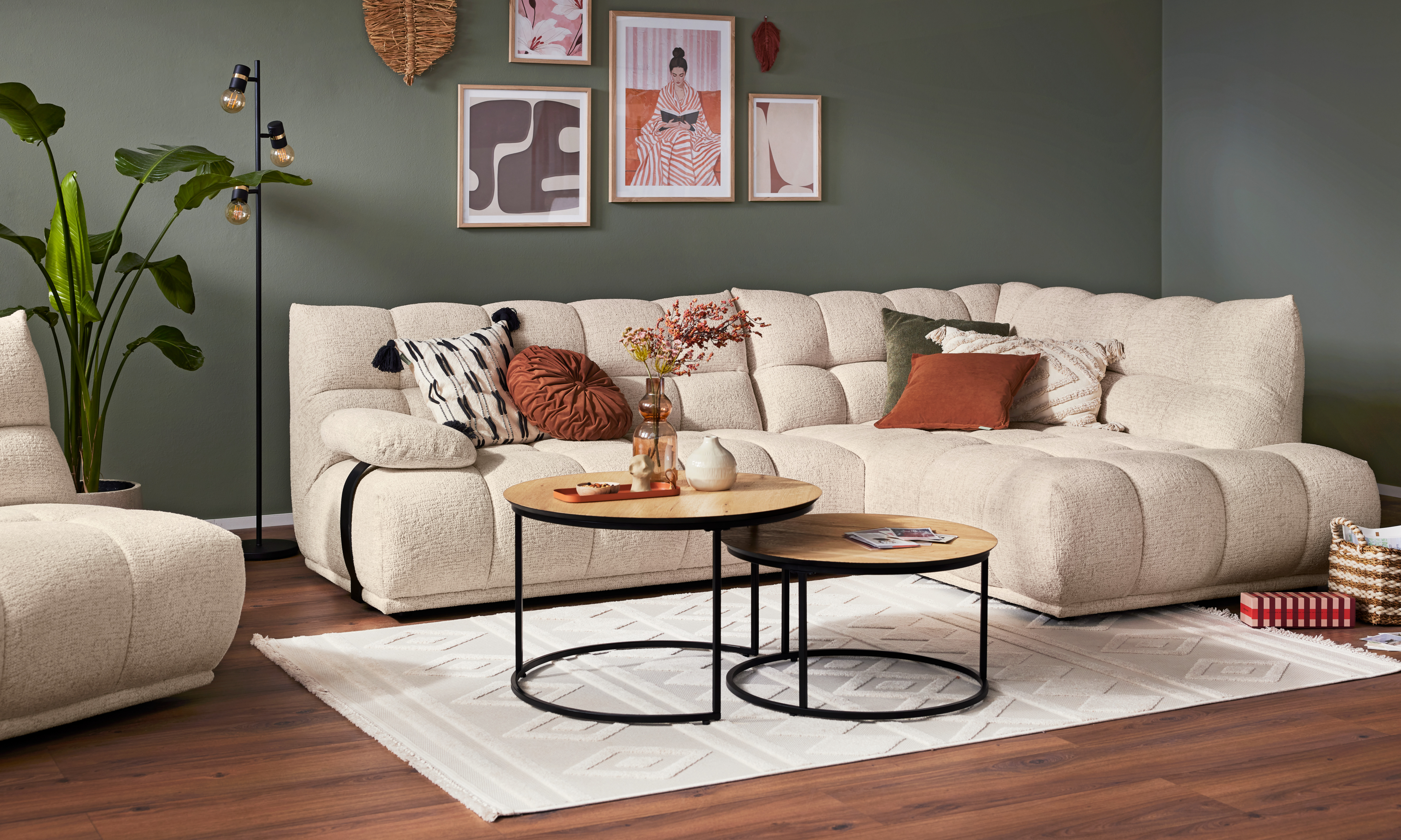 Bouclé-Ecksofa mit rundem Couchtisch-Set vor grüner Wand