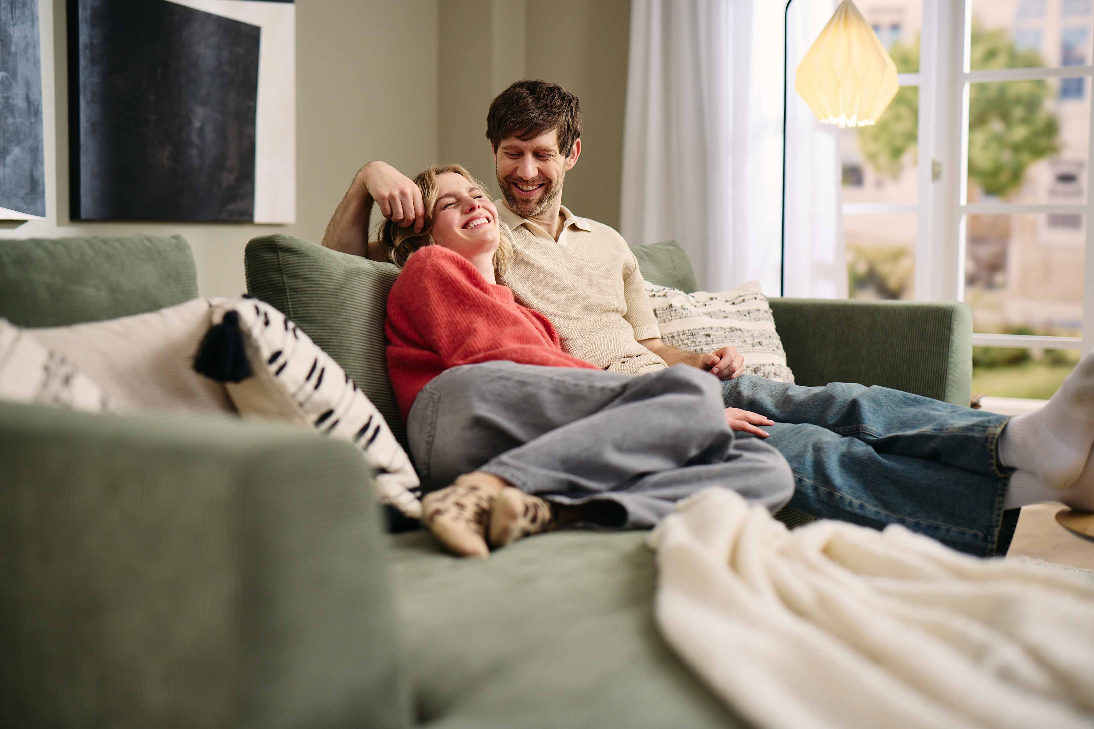 Paar entspannt gemeinsam auf einem grünen Roomio Sofa.