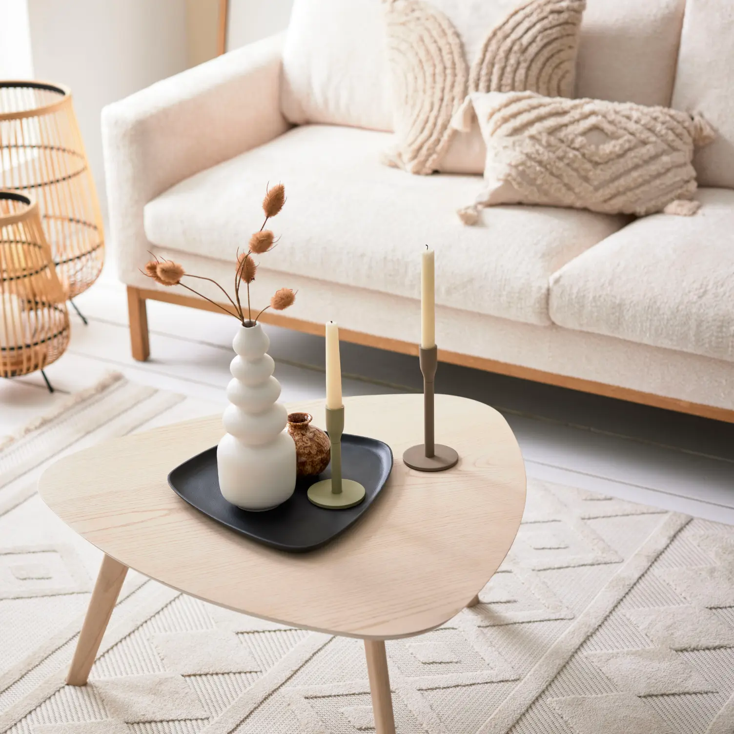 Helles Wohnzimmer mit beigem Sofa, strukturierten Kissen und organisch geformtem Couchtisch aus Holz – skandinavisches Wohnkonzept mit dekorativer Keramik und Teppich im Naturlook.