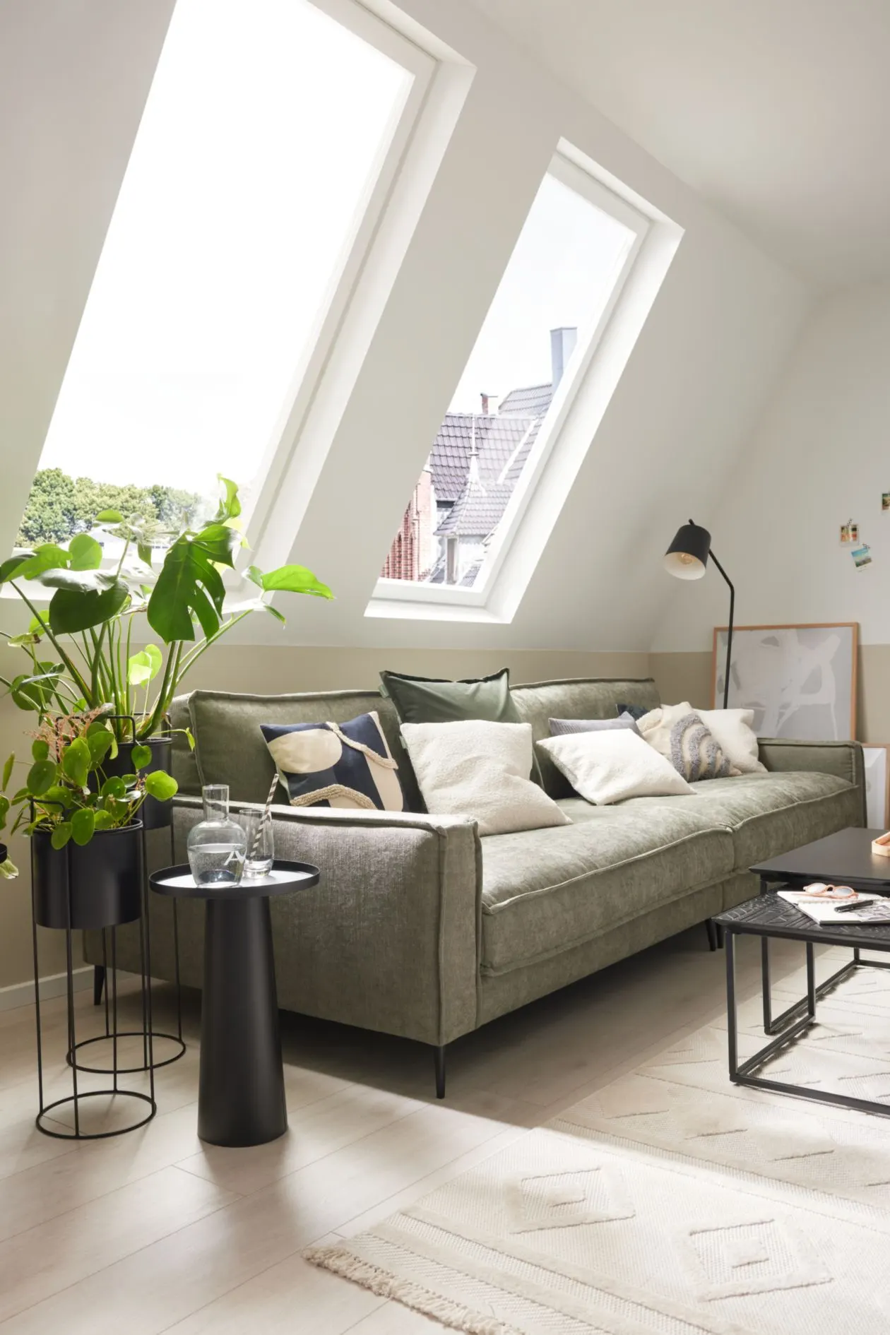 Dachgeschosswohnzimmer mit graugrünem Sofa und vielen Pflanzen