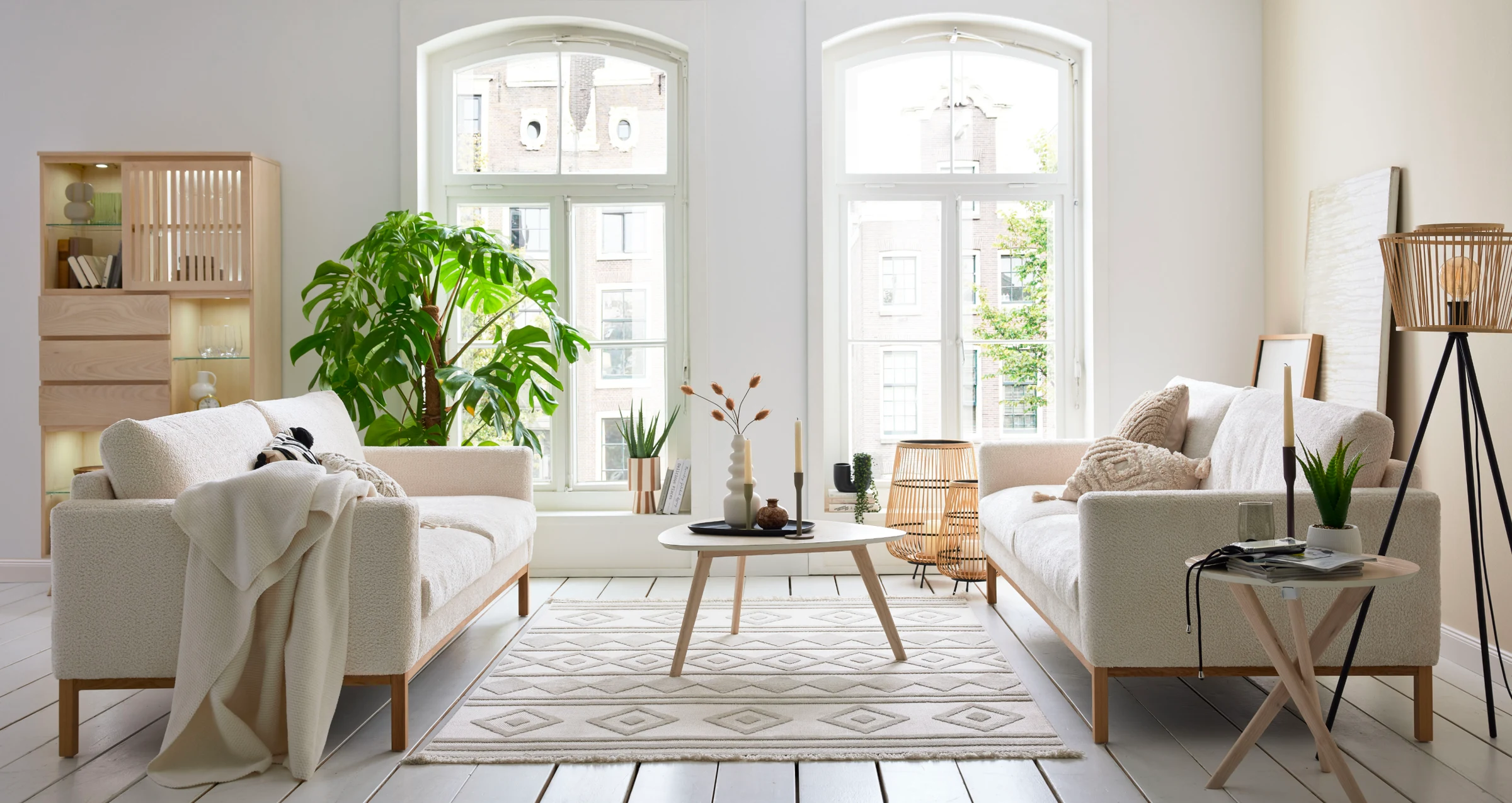 Symmetrisch eingerichtetes Wohnzimmer mit zwei beigefarbenen Roomio Sofas No. 4105, rundem Couchtisch und großem Fenster – helles, natürliches Interior-Konzept.