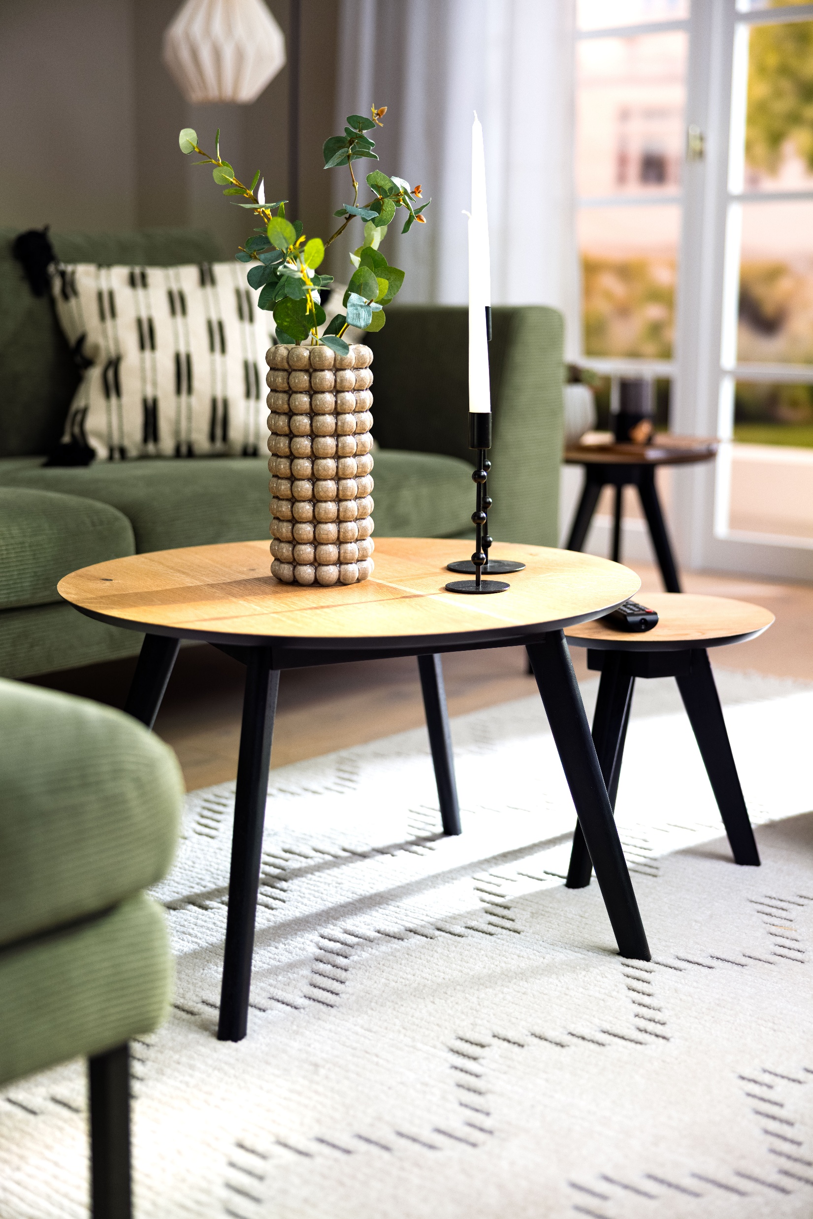 Eiche-Couchtisch mit Vase vor dem grünen Sofa