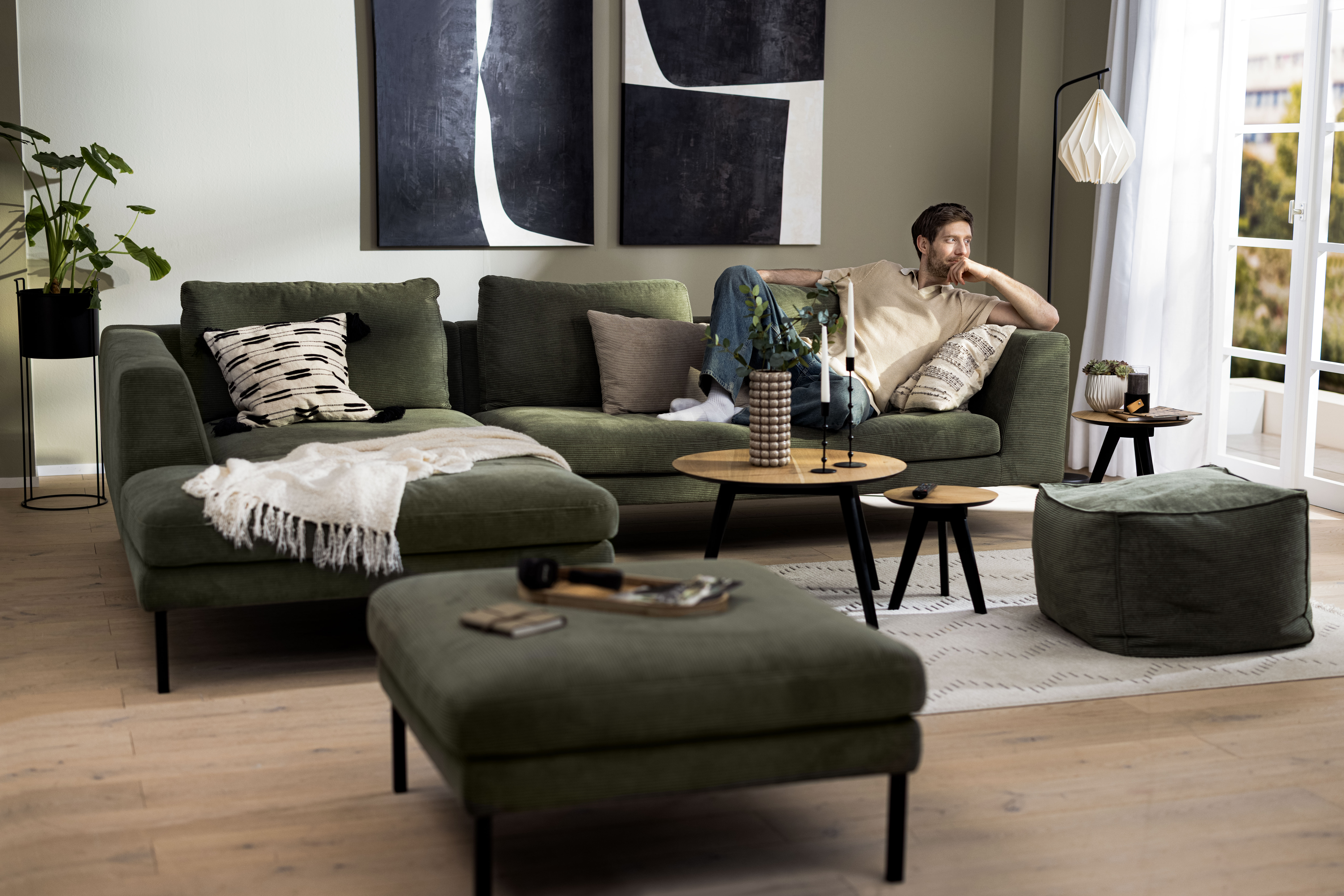 Jonas auf einem grünen Cord-Ecksofa im Wohnzimmer