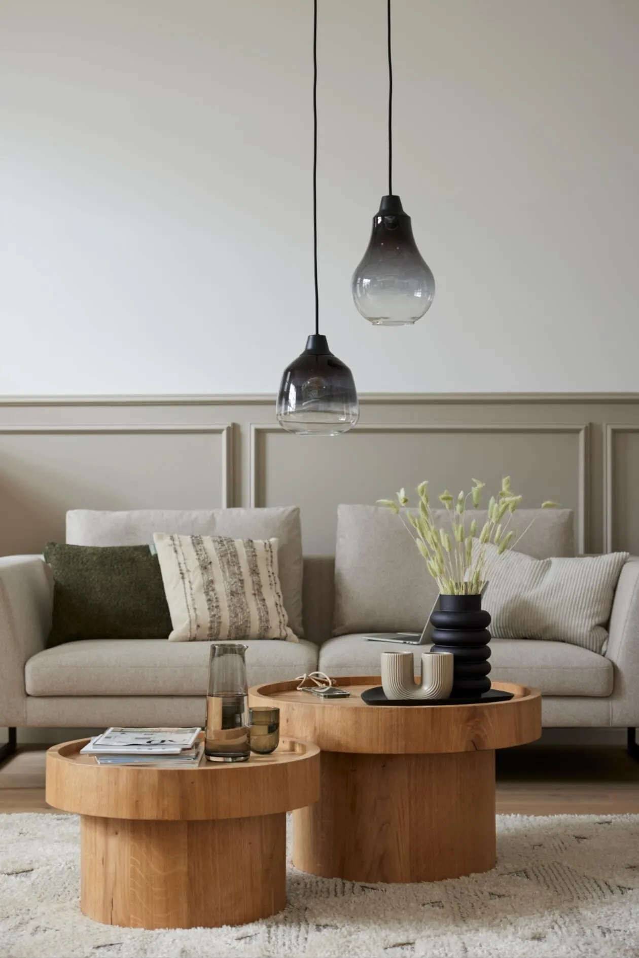 Helles Wohnzimmer mit beigem Sofa, Glas-Pendelleuchten und runden Holztischen