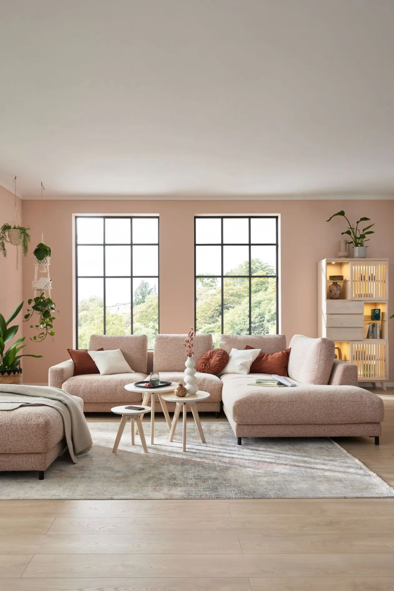 Helles Wohnzimmer mit Sprossenfenstern und beigem Sofa mit Ottomane